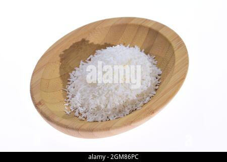 Coconut shavings in a wooden bowl against a white background. Stock Photo