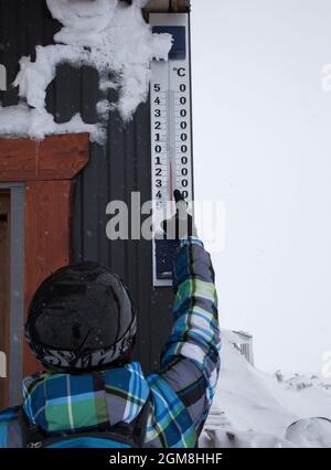 ski resort, a man skier in a helmet points to a large outdoor thermometer. On a scale of minus 8 degrees Celsius. Winter activity rest. Healthy lifest Stock Photo