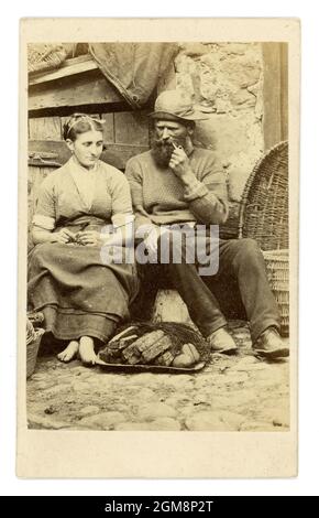 Original Victorian CDV (Carte de Visite) greetings card, made for the holiday trade at the time. Depicts a fisherman, smoking a pipe, wearing a traditional fisherman's jumper, with his wife who is barefoot at Cullercoats, Northumberland, Northern England, U.K. Circa 1860. Stock Photo