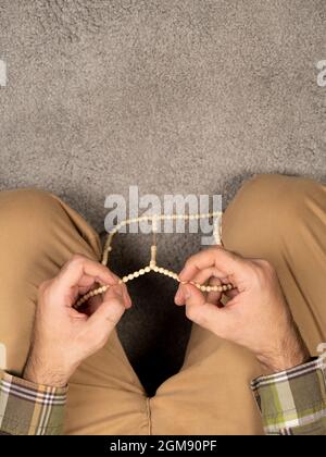 rosary in hands.  muslim man praying after prayer on grey rug. top view. copy space Stock Photo