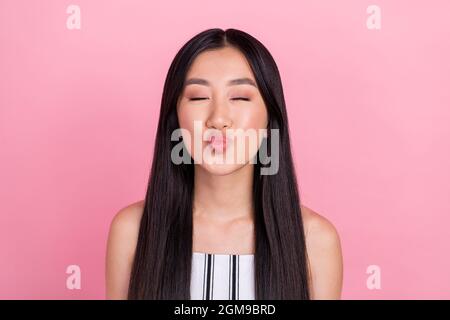 Photo of young flirty brunette lady blow kiss wear white overall isolated on pink color background Stock Photo