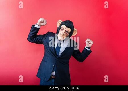 Businessman in euphoric monkey mask raising his fists. Stock Photo