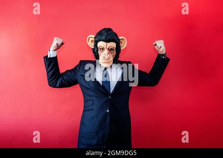 Businessman in euphoric monkey mask raising his fists. Stock Photo