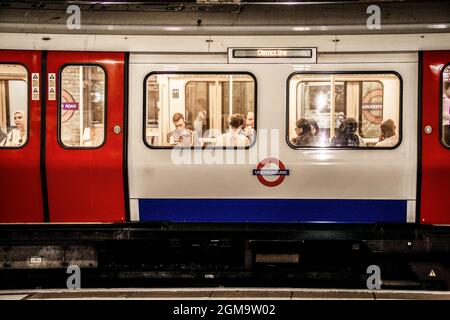 7 - 2 - 2019 London UK - Underground train in tunnel in London - District Line with people viewed inside showing through windows Stock Photo