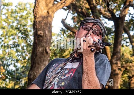 2019 09 15 Sweaty man with Gary nametag really getting into playing he fiddle outdoors on a very hot day - close-up and selective focus. Stock Photo