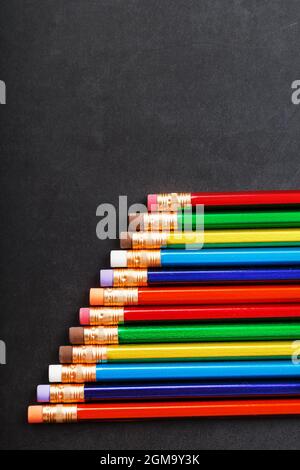 Colorful pencils with erasers in a row on a black background. Top view, free space Stock Photo