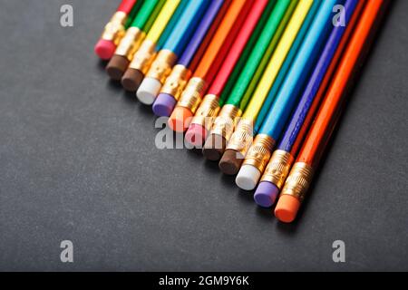 Colorful pencils with erasers in a row on a black background. Top view, free space Stock Photo