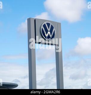 VW Volkswagen car logo and sign outside car dealer showroom, Exeter Stock Photo