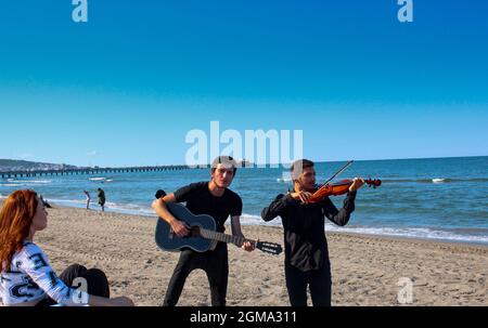 two young guys doing serenade to a girl to impress her. lucky girl have boys around. Stock Photo