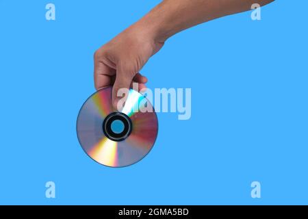 Scratched CD in your hand on a blue background, outdated technologies Stock Photo