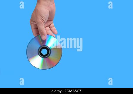 Scratched CD in your hand on a blue background, outdated technologies Stock Photo