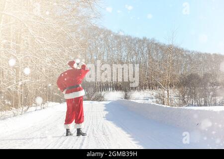 Santa Claus comes with gifts from the outside. Santa in a red suit with a beard and wearing glasses is walking along the road to Christmas. Father Chr Stock Photo