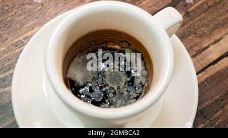 Black moldy coffee, fungus blooming coffee drink in a cup. Stock Photo