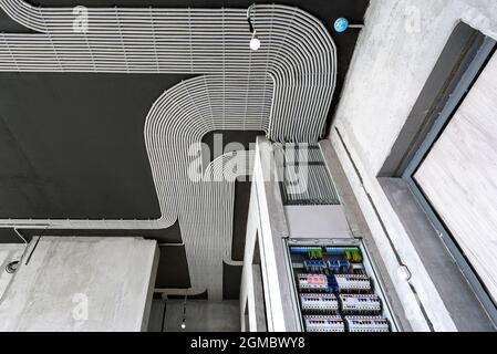Electrical cables and switch box on house concrete ceiling and wall. Modern plastic hoses with wires in room. Lines of pvc wiring tubes after professi Stock Photo