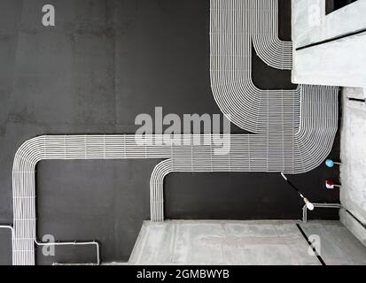 Electrical cables and pipes on house concrete ceiling background, plastic hoses with wires in empty room. Lines of pvc wiring tubes after professional Stock Photo