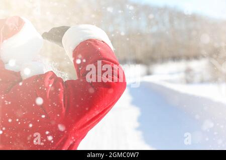 Santa Claus comes with gifts from the outside. Santa in a red suit with a beard and wearing glasses is walking along the road to Christmas. Father Chr Stock Photo