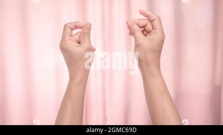 Hands snapping fingers isolated on pink background. Isolated female hands flicking fingers to the rhythm of the music. Sign language. Stock Photo