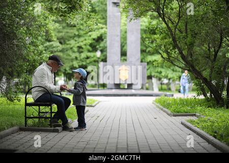 Grandpa is walking with her grandson in a spring park. Grandson and grandfather on walk. Grandpa is talking to a little boy. Stock Photo