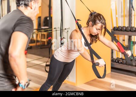 Woman doing exercise with fitness straps in gym Stock Photo