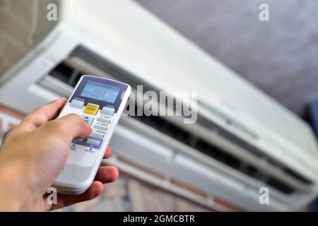 Hand holding ac remote changing temperature Stock Photo