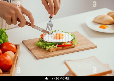 Closeup of the hands of young man preparing a sandwich at home Stock Photo