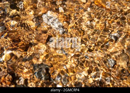 Abstract creek bed through clear flowing stream water with interference pattern Stock Photo