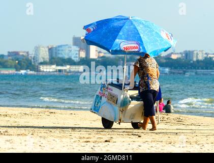 Anapa, Russia, 2021: an ice cream saleswoman seller moves a mobile retail cart branded Nestle along city beach Stock Photo