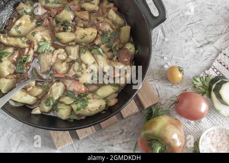 There are delicious zucchini fried with various vegetables on the table in a cast-iron frying pan. Top view, close-up. Stock Photo