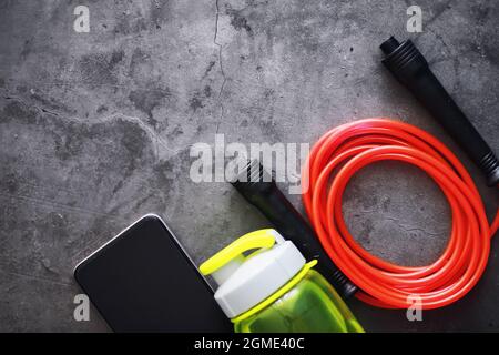 Jump rope. Physical education. Sports exercise equipment. Rope exercises routine. Pink jump rope stopwatch and water on the table. Stock Photo