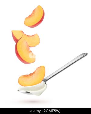 Isolated yogurt with fruits. Spoon with natural yogurt and falling slices of peach fruit isolated on white background Stock Photo