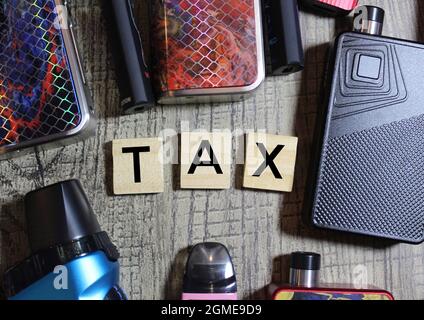 Top view of e-cigarette vaping kit and wooden cube with TAX written on it Stock Photo