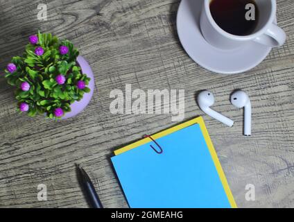 Wooden table desk with blank color memo pad, coffee and earphones. Top view and copy space for text. Stock Photo