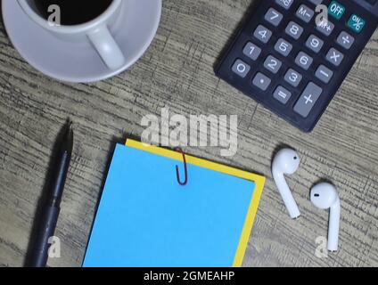 Top view of wooden table with cup of coffee, calculator, pen and blank color notepaper. Stock Photo