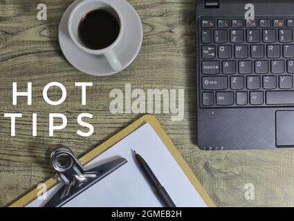 Top view of coffee, pen, laptop, paper clipboard and HOT TIPS text. Stock Photo