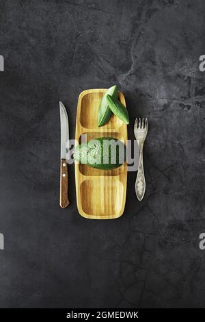 Avocado cooking recipes. Ripe green avocado on a wooden cutting board serving. Stock Photo