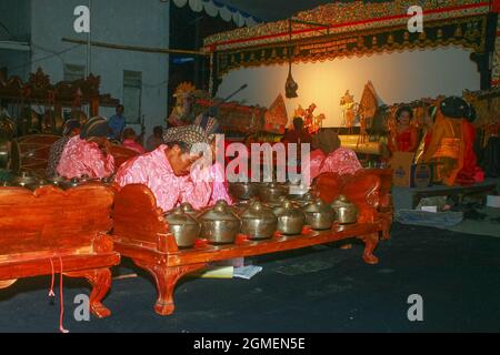 Gamelan musicians dressed in traditional Javanese costumes accompany a shadow puppet show. Puppets show are usually staged all night long. Stock Photo
