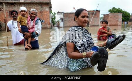 The rural village people are going to safe home from their own home due to flood at Varanasi, Uttar Pradesh in India in the year 2013. Stock Photo