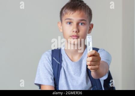 Teenage boy with backpack shows rapid Coronavirus Covid-19 negative test device with negative test result Stock Photo