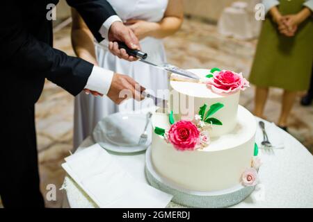 White wedding cake with flowers on a wooden table. Stock Photo