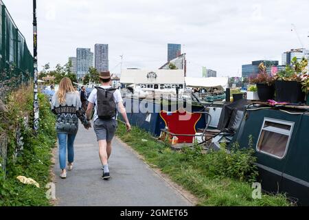 Couple walk along the Hertford Union Canal near Fish Island, Hackney Wick, London, looking towards Stratford. Stock Photo