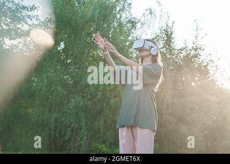 A girl wearing virtual reality glasses. He holds out his hands to the beam of sunlight. High quality photo Stock Photo