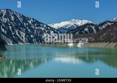 TOYAMA, JAPAN – APRIL 28, 2018: Landscape view of Kurobe dam in sunny day with clear blue sky at The Tateyama Alpine Route or Japan Alps snow wall. Pr Stock Photo