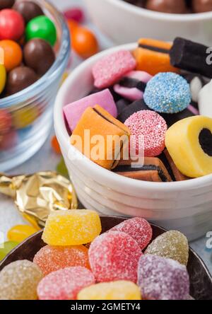Liquorice Allsorts Sweets mixed in white ceramic plate on light table with jelly sugar candies and chocolate bonbons. Stock Photo