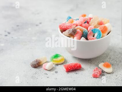 Fruit flavour gums candies with a sour sugar coating in ceramic bowl on light table Stock Photo