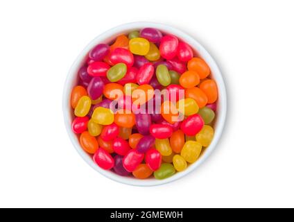 Various jelly beans sweet gummy candies in ceramic plate on white background. Top view Stock Photo