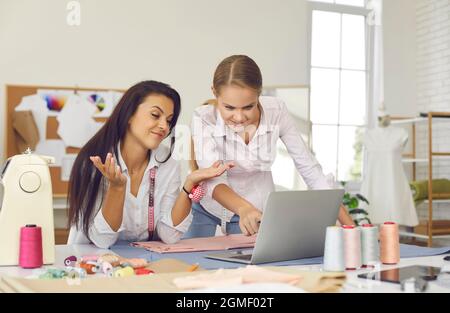 Two women who own small dressmaking business using laptop in their sewing atelier Stock Photo