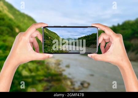 hand holding smartphone taking landscape image, mobile photography concept Stock Photo