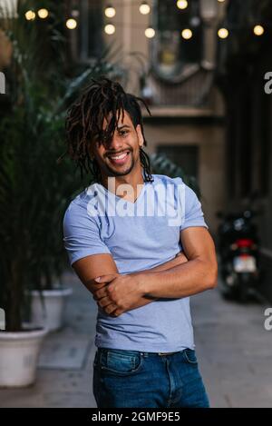 vertical portrait of an hispanic young man with dreadlocks. He is looking at camera and smiles Stock Photo