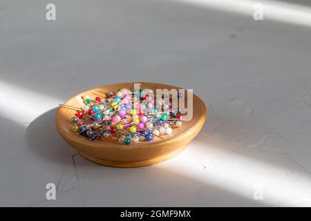 colored sewing pins in a golden plate against grey background with abstract light and shadow Stock Photo