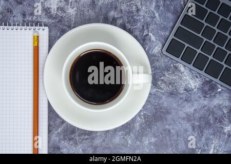 Workspace with keyboard, stationery, pencil, notepad and coffee cup on gray table. Flat lay, office table top view. The concept of business financing Stock Photo